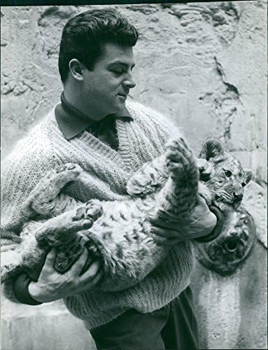 Гроздобер фотографија на човек кој носи младенче од леопард.